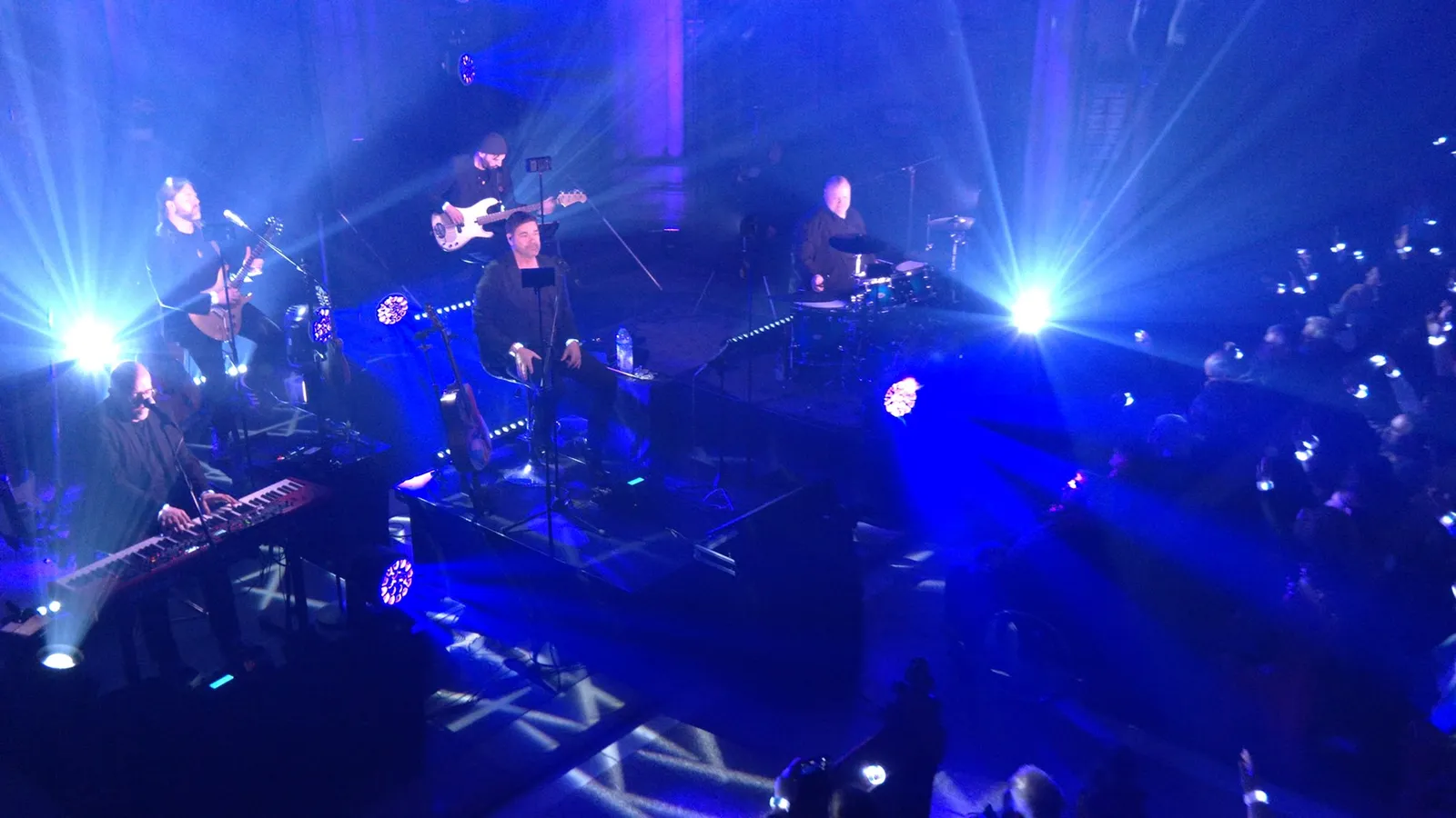 Die Band von oben gesehen, in blauem Licht mit Lichtkegeln