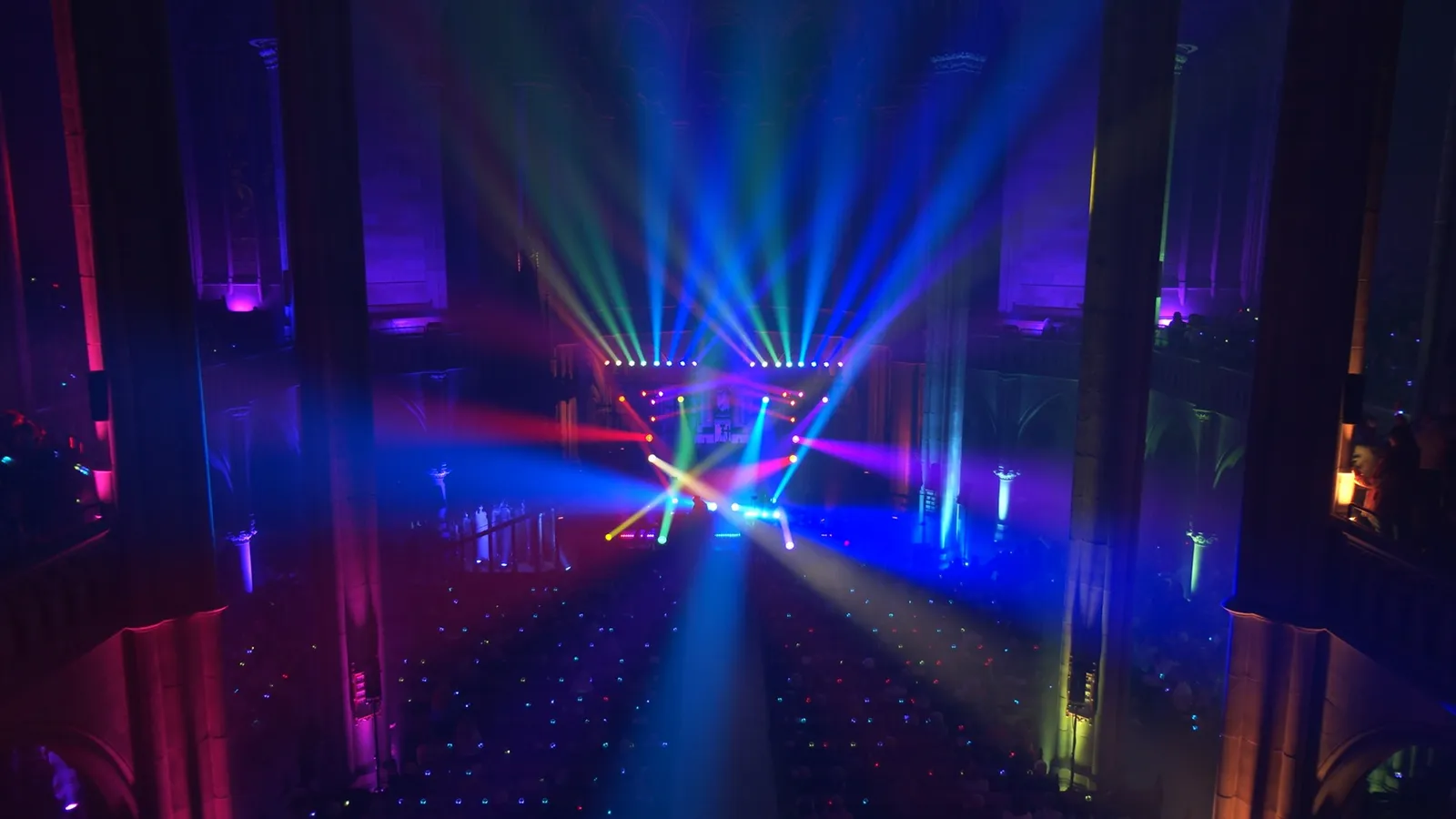 Bunte Laser und Lichtfächer im großen Kirchenschiff über dem Publikum