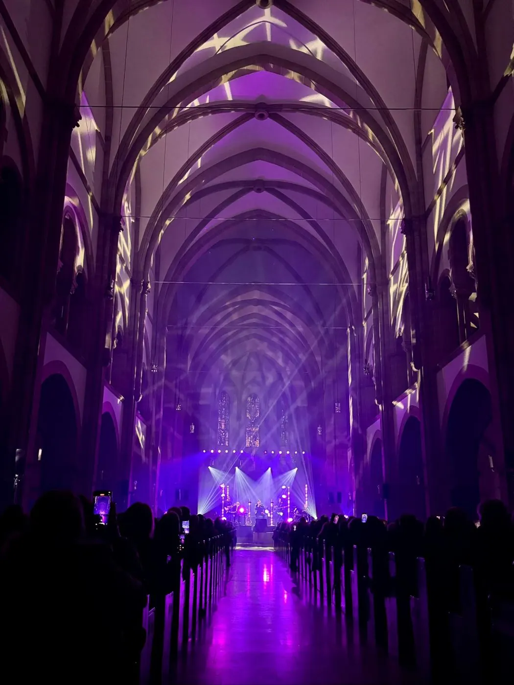 Kirchenschiff in violettem Licht mit Bühne und Publikum